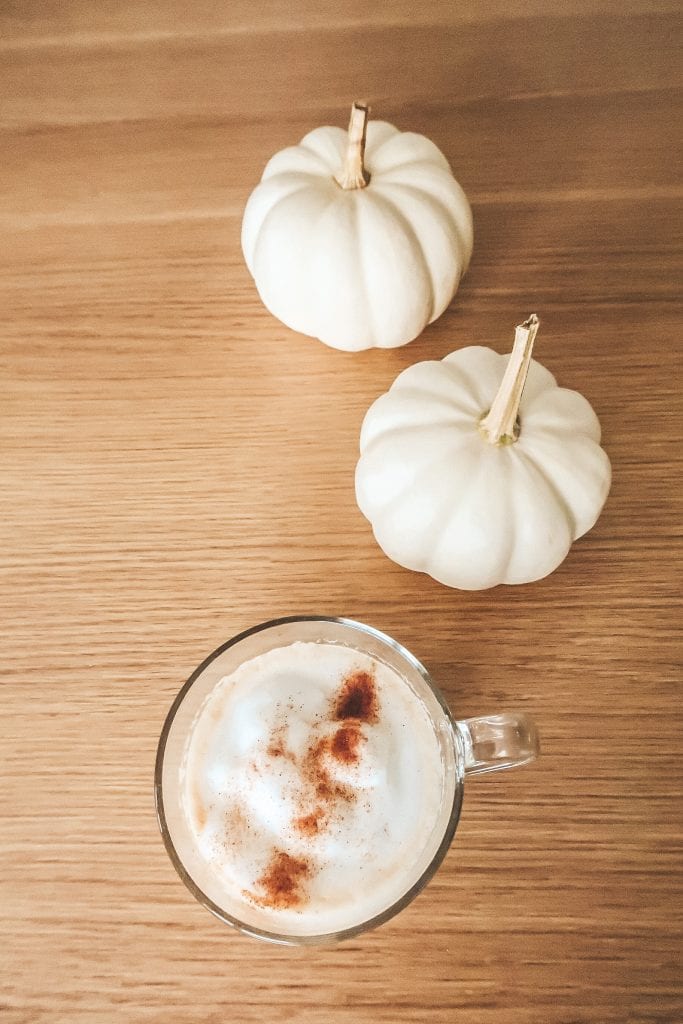 pumpkin spice latte e zucche bianche su tavolo in legno